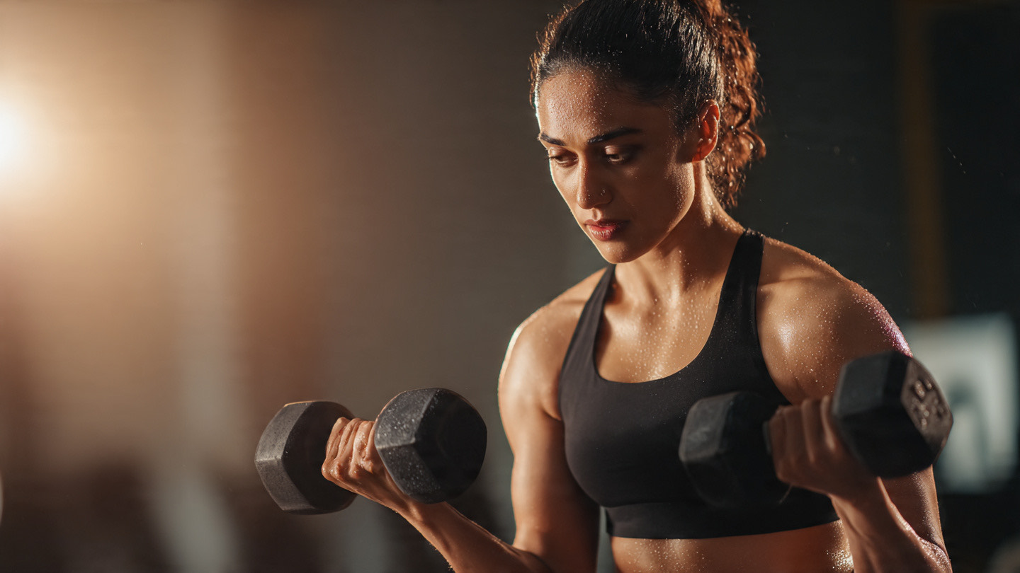 Indian woman doing intense dumbbell workout